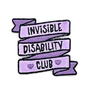 May include: A purple embroidered patch with the words "INVISIBLE DISABILITY CLUB" in black lettering. The patch has a banner design with a fuzzy texture and two small heart shapes.