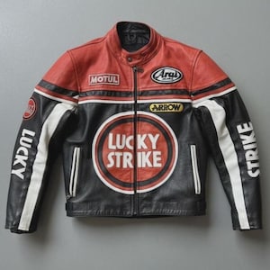 May include: A red, black, and white leather motorcycle jacket with the "Lucky Strike" logo prominently displayed on the front. The jacket features "MOTUL" and "Arai" patches, with "LUCKY" and "STRIKE" printed on the sleeves. The jacket has a classic biker style.