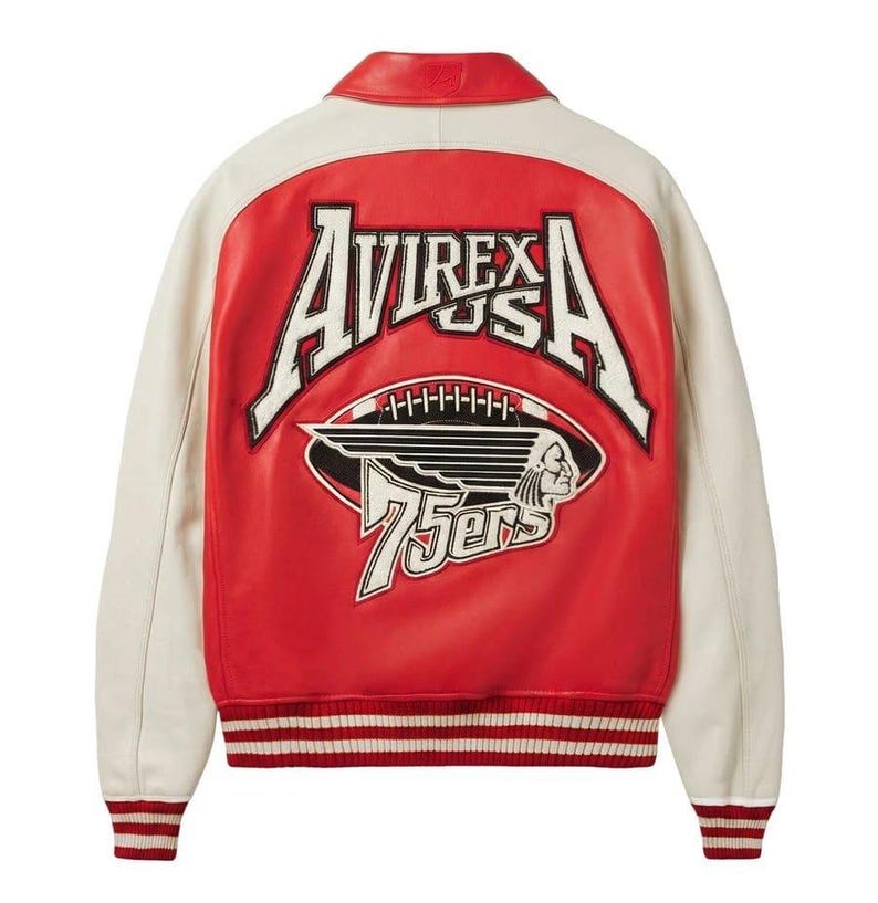 Puede incluir: Chaqueta de cuero roja y crema con el texto "AVIREX USA" y un gr&aacute;fico de f&uacute;tbol con un perfil nativo americano. La chaqueta tiene dobladillo y pu&ntilde;os acanalados, y el n&uacute;mero "75ers" se muestra debajo del gr&aacute;fico de f&uacute;tbol.