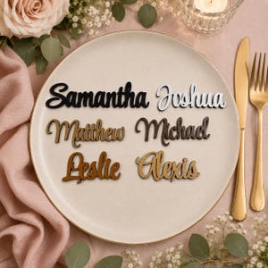 May include: Six custom name cutouts in various colors and wood finishes arranged on a round plate. The names Samantha, Joshua, Matthew, Michael, Leslie, and Alexis are written in a cursive script font, showcasing different material textures.