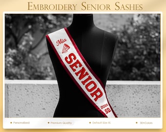 Puede incluir: Banda de graduación bordada en blanco y rojo con el nombre "Mia" y "SENIOR 2026 SD" en letras rojas. La banda está colocada sobre un maniquí negro, con las palabras "EMBROIDERY SENIOR SASHES" en la parte superior.