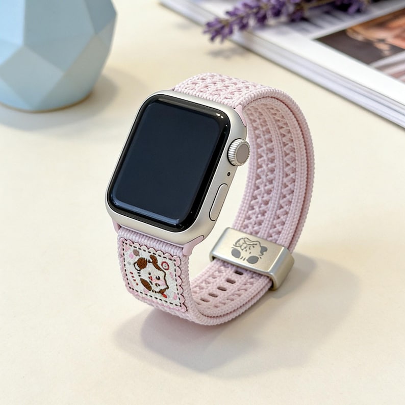 Close-up detail of the soft girl aesthetic watch strap, highlighting the delicate pointelle woven material and the adorable, colorful cartoon pet patch.
