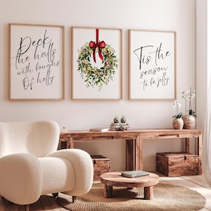 Puede incluir: Tres impresiones enmarcadas con temas navideños. La impresión de la izquierda dice "Deck the halls with boughs of holly". La impresión central presenta una corona con un lazo rojo. La impresión de la derecha dice "Tis the season to be jolly".