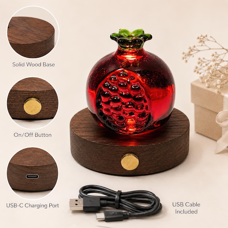 May include: A decorative red glass pomegranate lamp with a green top, resting on a dark wood base. Features include an on/off button and a USB-C charging port. A USB cable is included. The base is approximately 4 inches in diameter.