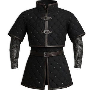 Puede incluir: Gambesón medieval acolchado negro con mangas cortas, ribetes de cuero marrón y hebillas metálicas. La prenda presenta un cuello alto, un cinturón y mangas de cota de malla. El patrón de diamantes está acentuado con pequeños tachuelas plateadas.