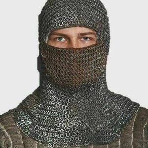 May include: A close-up of a chainmail coif, a type of medieval head covering. The coif is made of small, interlocking metal rings, covering the head, neck, and face. The metal has a silver-gray color. The person's eyes are visible.