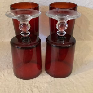 May include: Set of four ruby red glass tumblers with clear glass stems. The glasses have a vintage look and are perfect for serving cocktails or other beverages.