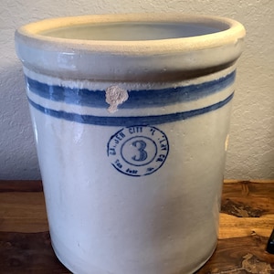 May include: A white ceramic crock with blue stripes and a blue and white circular stamp that reads "The John City Clay Co. 3".