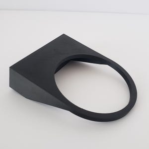 May include: A black, geometric, 3D-printed object with a square top and a circular opening. The object has a smooth, matte finish and a minimalist design. The object is likely a holder or a stand.