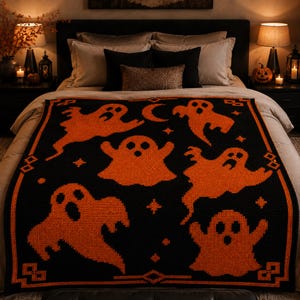 May include: A black and orange knit blanket featuring a repeating pattern of various ghost shapes, small stars, and a crescent moon. The blanket is finished with a geometric border design in orange, creating a distinct contrast against the black background.