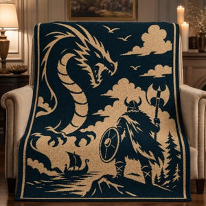 May include: A dark blue and beige woven throw blanket featuring a large dragon on the left side and a warrior wearing a horned helmet, holding a shield and a battle axe, standing on a rocky cliff overlooking a small sailing ship on the water.