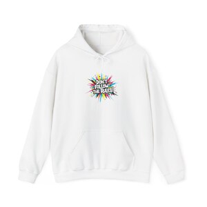 May include: White hoodie with a front pocket and drawstring hood. The front features a colourful graphic that reads "DON'T FOLLOW THE RULES!" in a bold, playful font. The hoodie is made of a soft material.