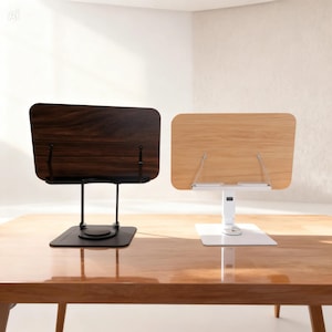 May include: Two wooden book stands. One stand has a dark brown wooden surface and a black base. The other stand has a light brown wooden surface and a white base. Both stands are on a wooden table.