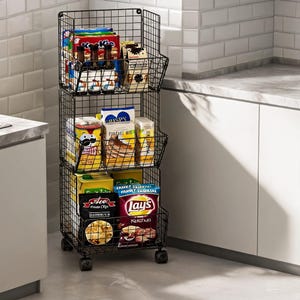 May include: A three-tier black metal wire storage cart with wheels, featuring open-front baskets filled with various food items including boxes of pancake mix, bags of potato chips, and bottles of sauce, providing organized vertical storage.