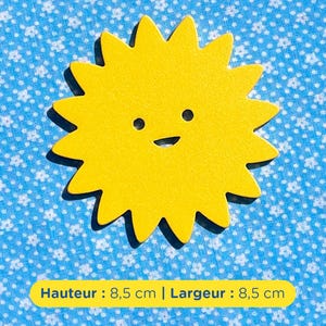 Peut inclure: Une découpe en forme de soleil jaune vif avec un visage simple composé de deux petits yeux circulaires et d'une bouche incurvée. L'objet mesure 8,5 cm de hauteur et 8,5 cm de largeur, comme indiqué par le texte sur l'étiquette jaune en dessous.