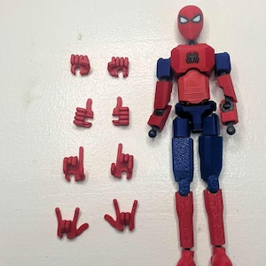 May include: A red and blue articulated action figure resembling Spider-Man, with interchangeable red hands in various gestures. The figure has a red head with white eyes, a red torso, blue arms and legs.