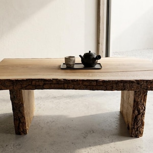 Könnte beinhalten: Ein Couchtisch aus Naturholz mit Baumkante und Baumstammbeinen. Eine schwarze Teekanne, eine Tasse und ein Tablett stehen auf dem Tisch. Der Tisch ist 120.6 cm lang, 83.8 cm breit und 69.9 cm hoch.