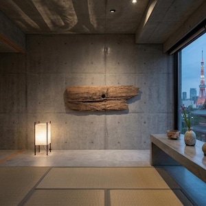 May include: A room featuring a concrete wall with a large piece of driftwood mounted on it, a floor lamp with a white shade, a long stone bench with three ceramic vessels, and a sliding shoji screen door overlooking a city skyline view.