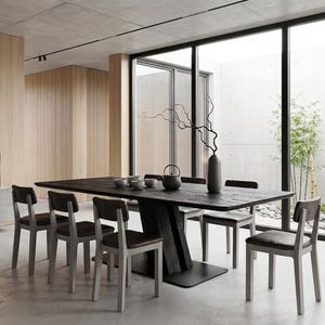 Puede incluir: Un comedor moderno con una mesa de madera oscura y seis sillas. La mesa está decorada con un jarrón, un juego de té y objetos decorativos. La habitación tiene grandes ventanales con vistas a un jardín zen, con paneles de madera clara y un techo de hormigón.