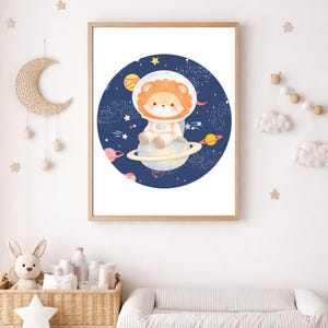 Könnte beinhalten: Gerahmter Druck mit einem Cartoon-Löwen in einem Astronautenanzug, der auf einem Planeten mit Ringen sitzt, vor einem dunkelblauen Weltraumhintergrund mit Planeten und Sternen. Das Kunstwerk ist in einem hellen Holzrahmen, ideal für ein Kinderzimmer.