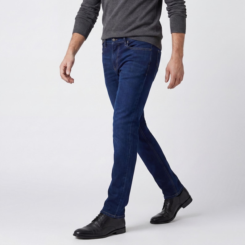 May include: A person wearing a dark gray sweater and dark blue jeans. The jeans are a classic five-pocket style. The person is also wearing black leather dress shoes.