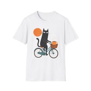 A plain white t-shirt featuring a graphic of a black cat riding a bicycle and carrying a cup of coffee.