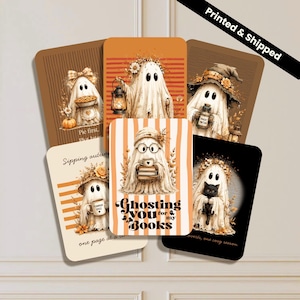 May include: A collection of five rectangular cards featuring illustrations of ghosts in autumn settings. One card shows a ghost holding books with the text Ghosting you for my books. Other cards depict ghosts with a pumpkin, lantern, potion, and black cat.