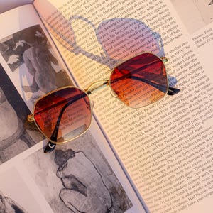 May include: A white ceramic mug with a black handle and the text "But First, Coffee" in a bold, black font. The mug is set against a blurred background, suggesting a cosy setting.