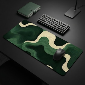 May include: A large, rectangular green and beige patterned mousepad with a black wireless mouse. A black keyboard and a green notebook are also on the black surface. The mousepad features a wavy design.