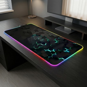 May include: Black rectangular gaming mouse pad with a honeycomb pattern and a colorful LED edge. The pad has a dark surface with green and blue accents, and a rainbow-colored border. The mouse pad is designed for gaming.