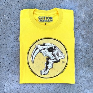 Smilodon Skull beautifully screen printed with 3 color inks on bright yellow t-shirt