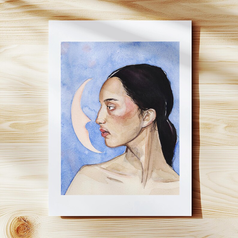 May include: Watercolor portrait of a woman in profile with dark hair and a crescent moon shape. The background is a blend of blue and white hues. The artwork is on a white paper.