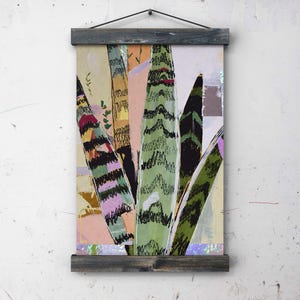 May include: Abstract art print of a snake plant, featuring green, black, pink, and yellow tones. The artwork is mounted on a wooden frame with a hanging cord, creating a modern, botanical-themed wall decor piece.
