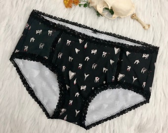 May include: Black underwear with a white lace trim and a graphic print of teeth.