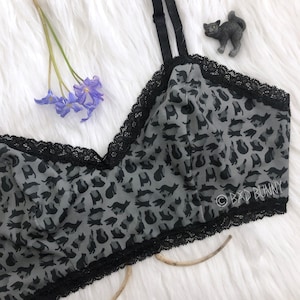 May include: A black lace bralette with a gray cat print and the text "Bad Bunny" on the bottom right corner.