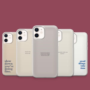Pode incluir: Cinco capas de telefone em vários tons de bege e cinza, cada uma com uma citação inspiradora diferente em uma fonte minimalista. As citações incluem "good things take time".