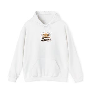 Op de afbeelding: Een witte hoodie met een centrale afbeelding van een s'more op een stokje, kleine vlammetjes en de tekst S'mores in bruin handschrift. Het kledingstuk is voorzien van een kangoeroezak aan de voorzijde, lange mouwen en een capuchon.
