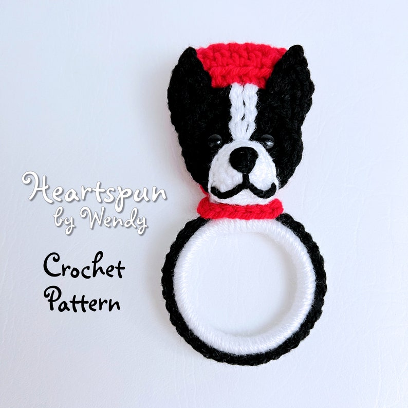 May include: Crochet pattern for a black and white Boston Terrier dog head with a red hat and scarf. The pattern is called "Heartspun by Wendy".