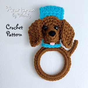 May include: Crochet pattern for a brown dog with a blue hat and a ring. The pattern is called "Heartspun by Wendy".