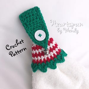 Puede incluir: Patrón de crochet para un adorno de toalla de temática navideña en verde y rojo con un botón blanco y una campana plateada. El patrón se llama "Heartspun by Wendy".