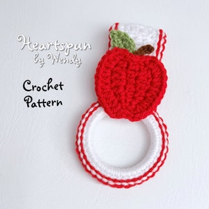 Puede incluir: Patrón de ganchillo para un agarrador de olla de manzana roja con ribete blanco y rojo. El patrón se llama "Heartspun by Wendy".