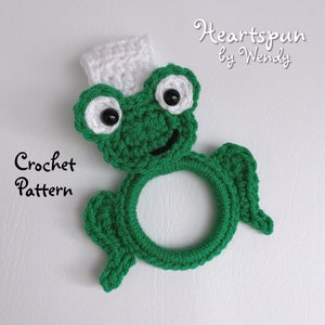 May include: Green crocheted frog ring toy with white crocheted hat and black eyes. Crochet pattern by Heartspun by Wendy.