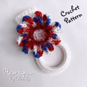 Puede incluir: Un patrón de crochet para una flor roja, blanca y azul con un centro rojo brillante. El patrón se llama "Heartspun by Wendy" y está disponible para descargar digitalmente.