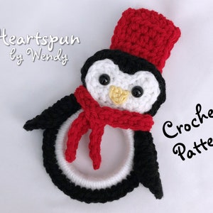 May include: Crochet pattern for a penguin ornament. The penguin is black and white with a red hat and scarf. The text "Crochet Pattern" is written in black cursive.