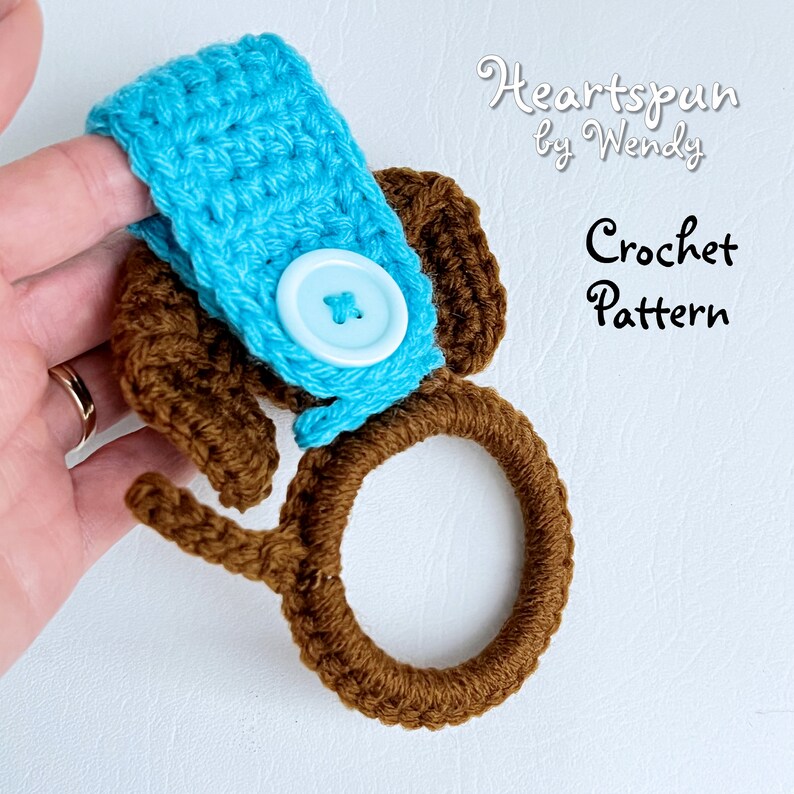 May include: Crochet pattern for a brown and blue towel ring with a button. The pattern is called "Heartspun by Wendy".