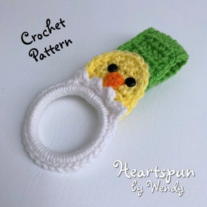 K&ouml;nnte beinhalten: H&auml;kelanleitung f&uuml;r einen Geschirrtuchring in Form eines wei&szlig;en und gelben K&uuml;ken mit gr&uuml;nem Hut. Das Muster hei&szlig;t "Heartspun by Wendy".