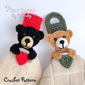 Könnte beinhalten: Zwei gehäkelte Teddybär-Handtuchhalter. Ein Bär ist schwarz mit einem roten Hut und einem roten Herzen. Der andere Bär ist braun mit einem grünen Hut und einem grünen Herzen. Der Text "Heartspun by Wendy Crochet Pattern" befindet sich am unteren Rand des Bildes.