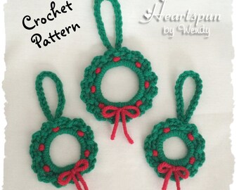 May include: Three crocheted Christmas wreaths with red bows and red dots. The wreaths are green and have a loop for hanging. The text "Crochet Pattern" is in the top left corner of the image. The text "Heartspun by Wendy" is in the top right corner of the image.