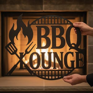 Könnte beinhalten: Ein rundes Schild aus schwarzem Metall mit dem Schriftzug BBQ LOUNGE in fetten Großbuchstaben. Das Design enthält eine Flammengrafik auf der linken Seite sowie einen gekreuzten Pfannenwender und eine Gabel, umrahmt von einem Grillrostmuster.