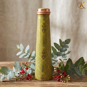 May include: A tall, olive-green water bottle with a copper-colored lid and base. The bottle is adorned with a repeating floral pattern in red and gold. The bottle is surrounded by green leaves and red berries, set against a wooden surface.